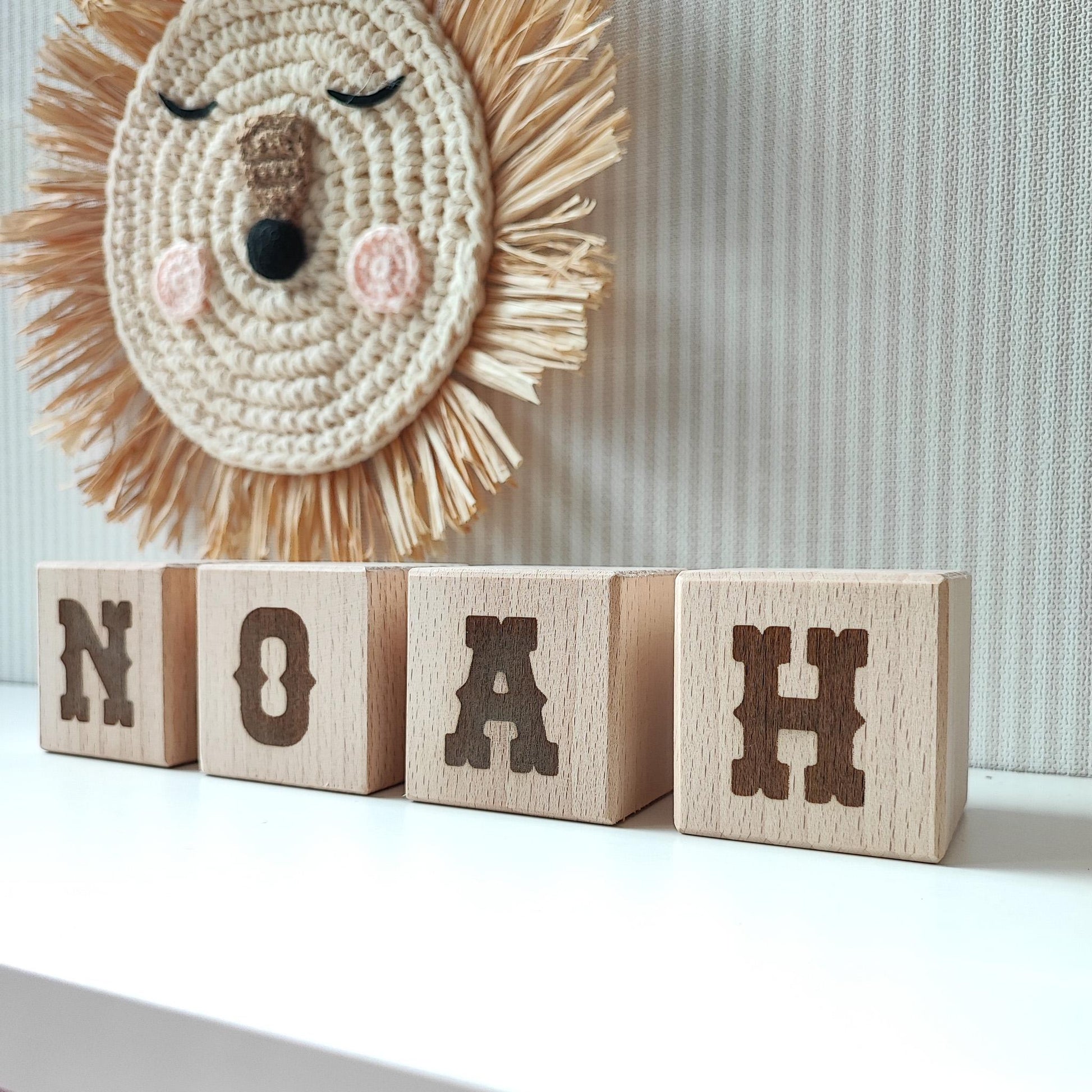 western style letters NOAH on wooden name blocks standing on a white shelf next to neutral nursery decor Lettrise