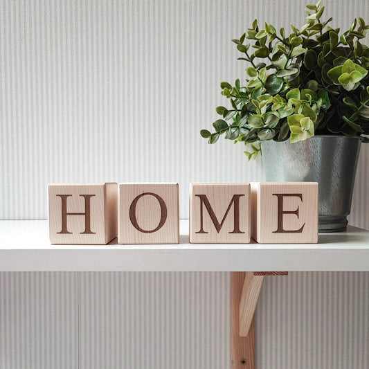4 wooden blocks spelling HOME letters evgrawed, standing on a shelf
